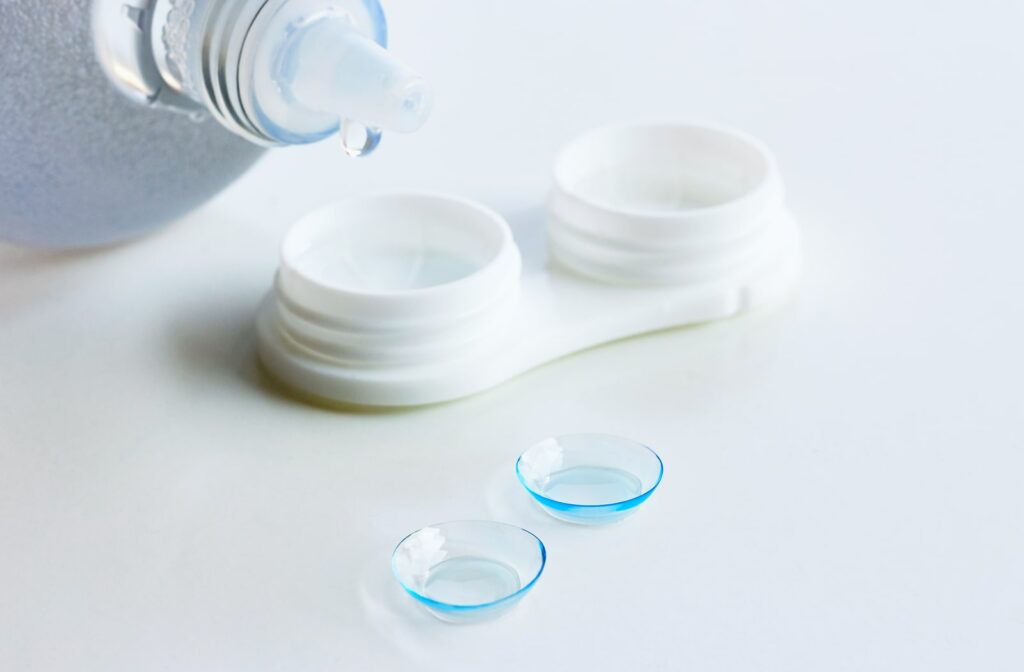 A bottle of contact lens solution, with a contact lens case and lenses sitting next to it