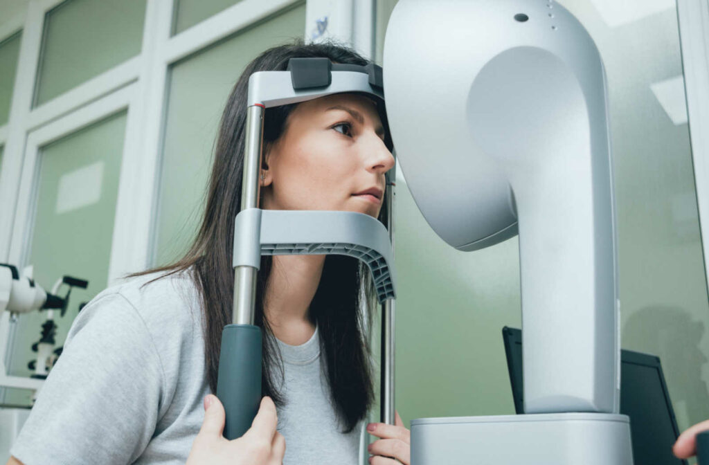 A patient leaning against the forehead and chin rest while undergoing a corneal topography test