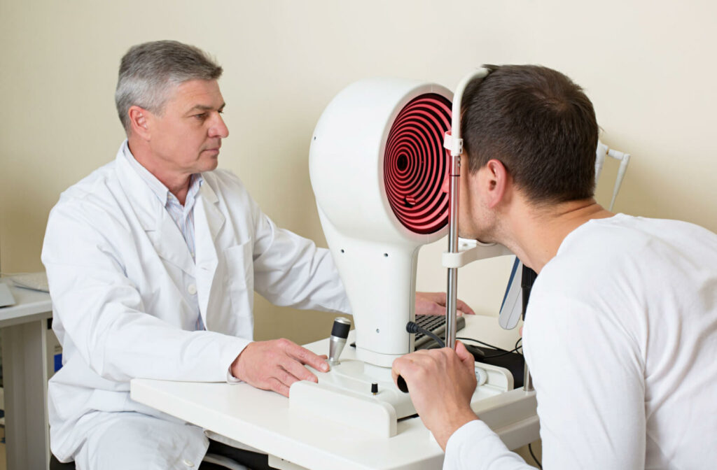 An optometrist performs a corneal topography test on a man patient who is experiencing blurry vision, a sign of Keratoconus