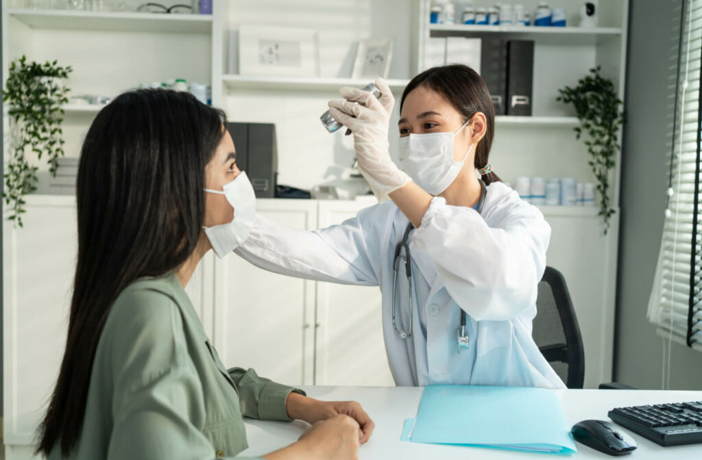 A female doctor uses a small flashlight in examining the patient's eye.