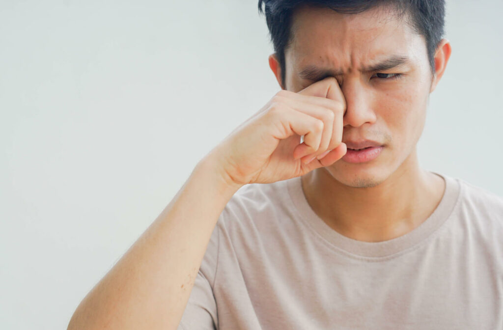 A close-up of a young man using his hand to rubbing eyes after feeling itchy because of conjunctivitis.