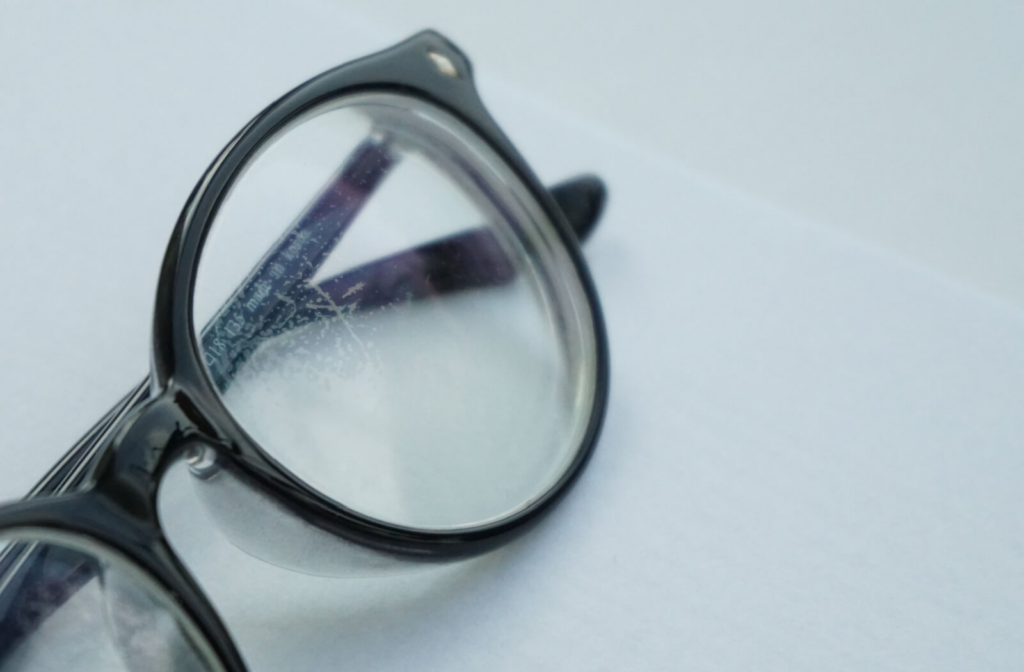 An eyeglass with heavy scratching and visible damage on the lenses.