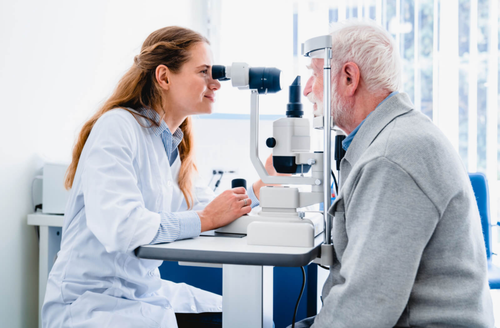 A female optometrist looking into a medical device to perform an eye exam on a senior man.