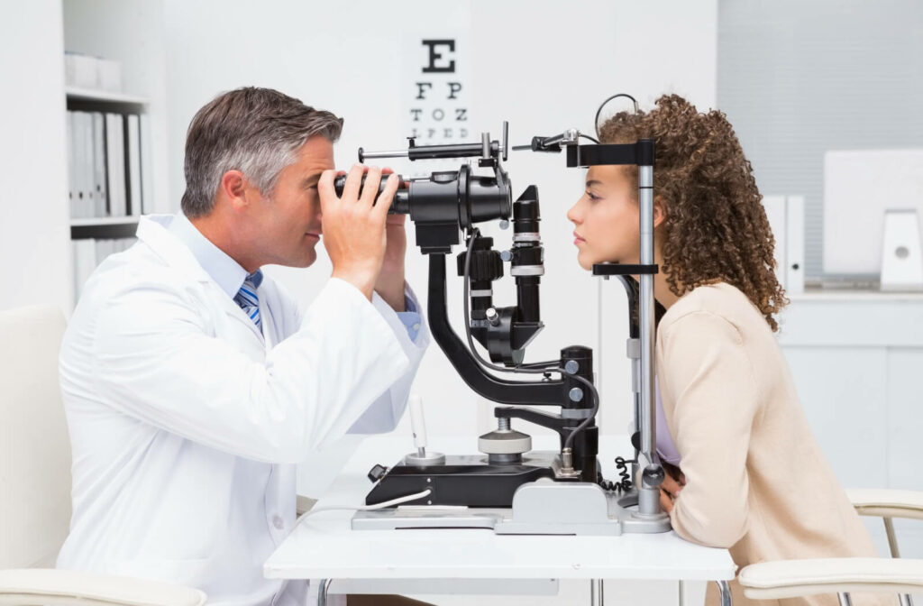 A male optometrist using a medical device to examine the eyes of a female patient and look for potential eye problems.