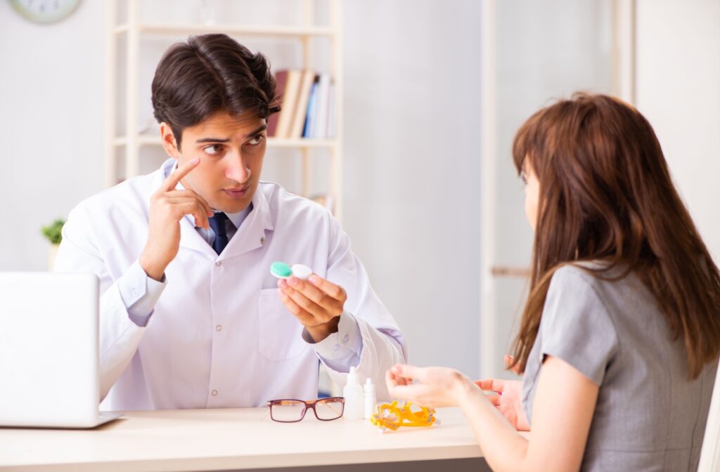 A young woman learns about proper contact lens use, wear, and care from her optometrist during her contact lens fitting.