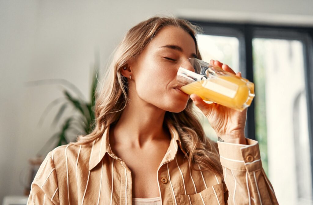 A person drinks a large glass of freshly squeezed orange juice at home.