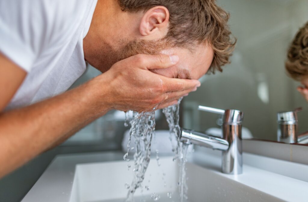 A man using water to flush his eye to remove something stuck in it