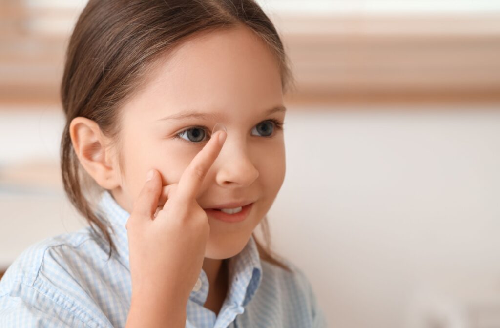 A happy child is about to put a contact lens into their eye to correct their myopia.