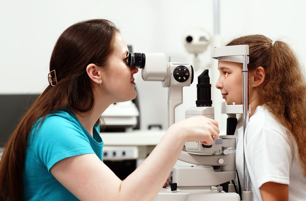 An eye doctor looking at a young patient's and using a slit lamp to determine the cause of their pink eye symptoms.